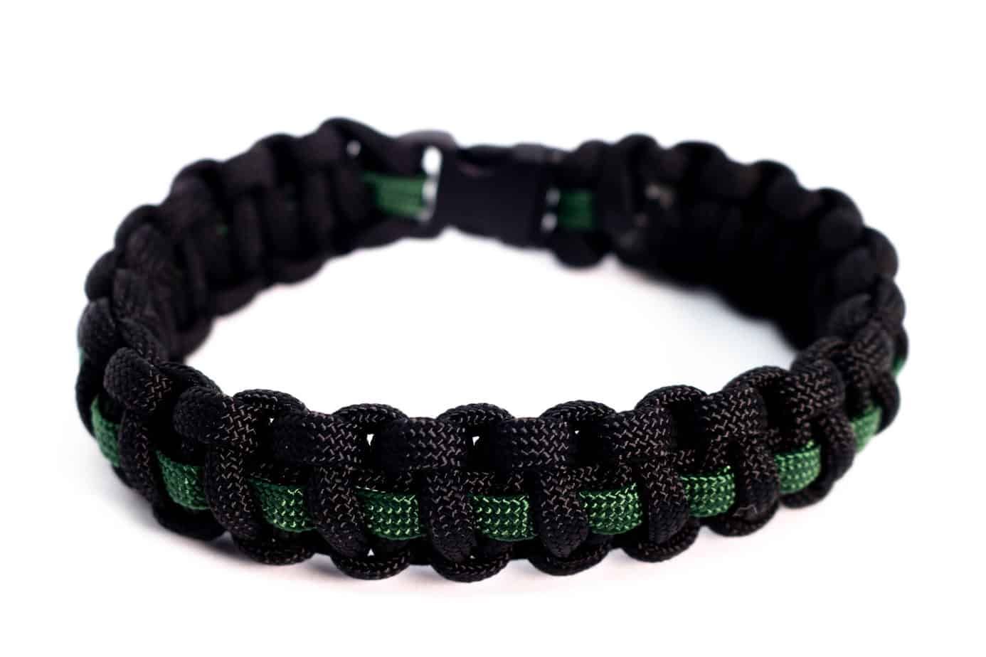 Black and green paracord bracelet with a thin green line; on white background.