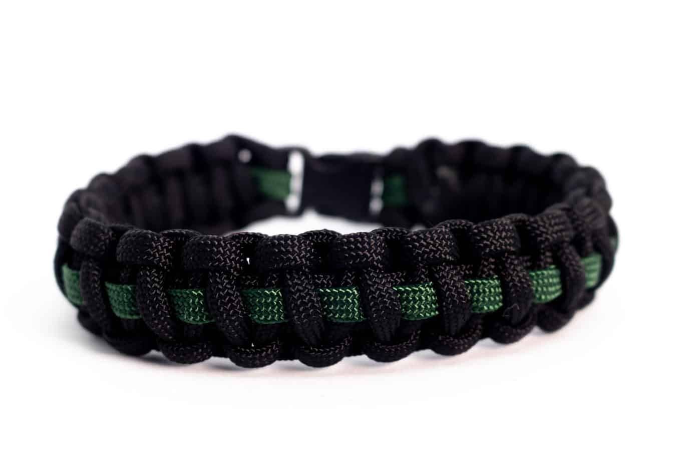 Black and green paracord bracelet with a thin green line; on white background.