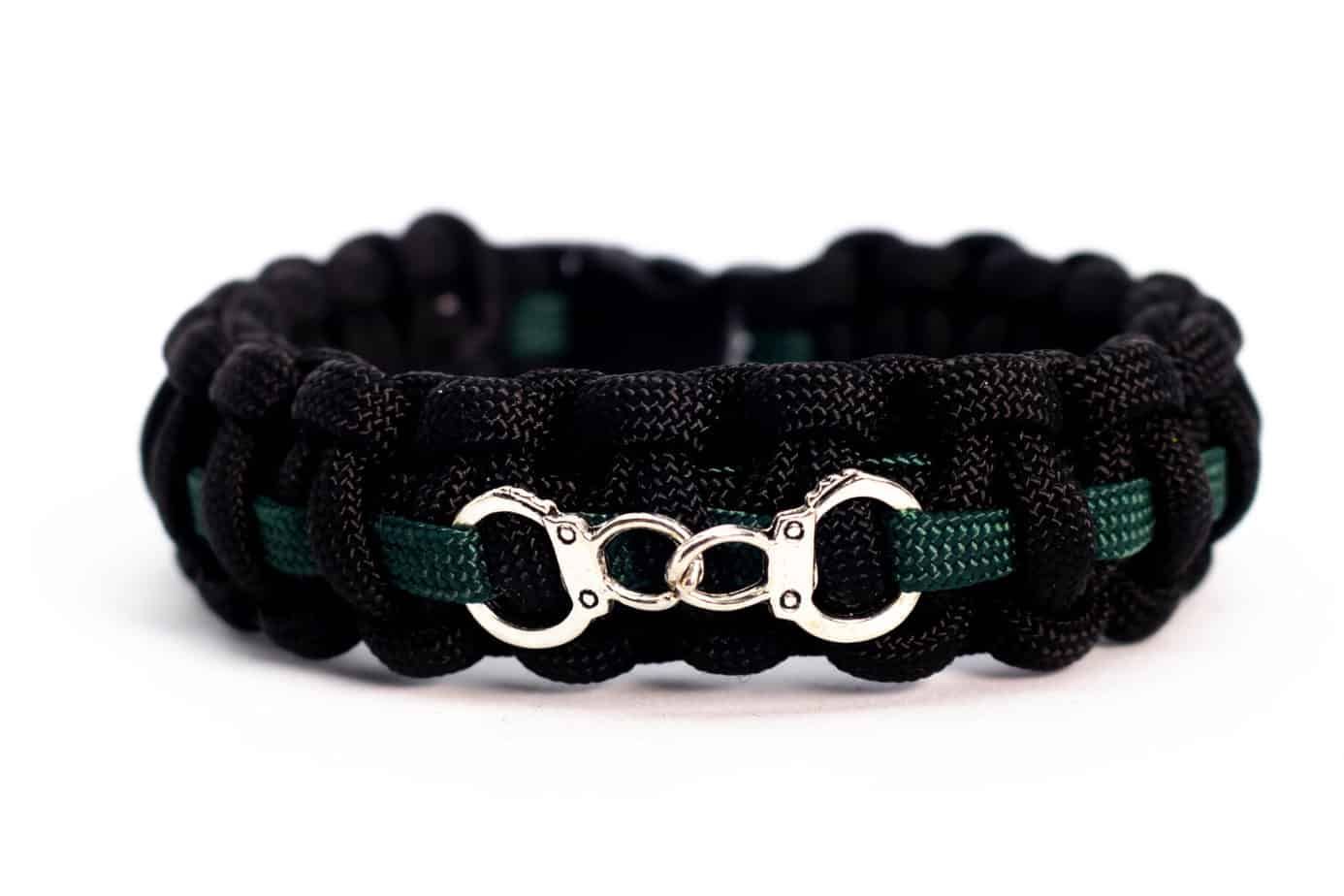 Black paracord bracelet with a green stripe and silver handcuff clasp.