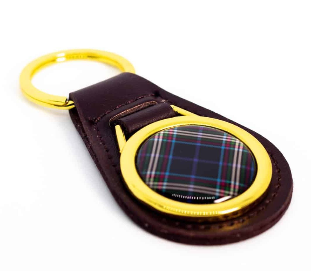 Dark brown leather keychain with gold ring and a plaid center.