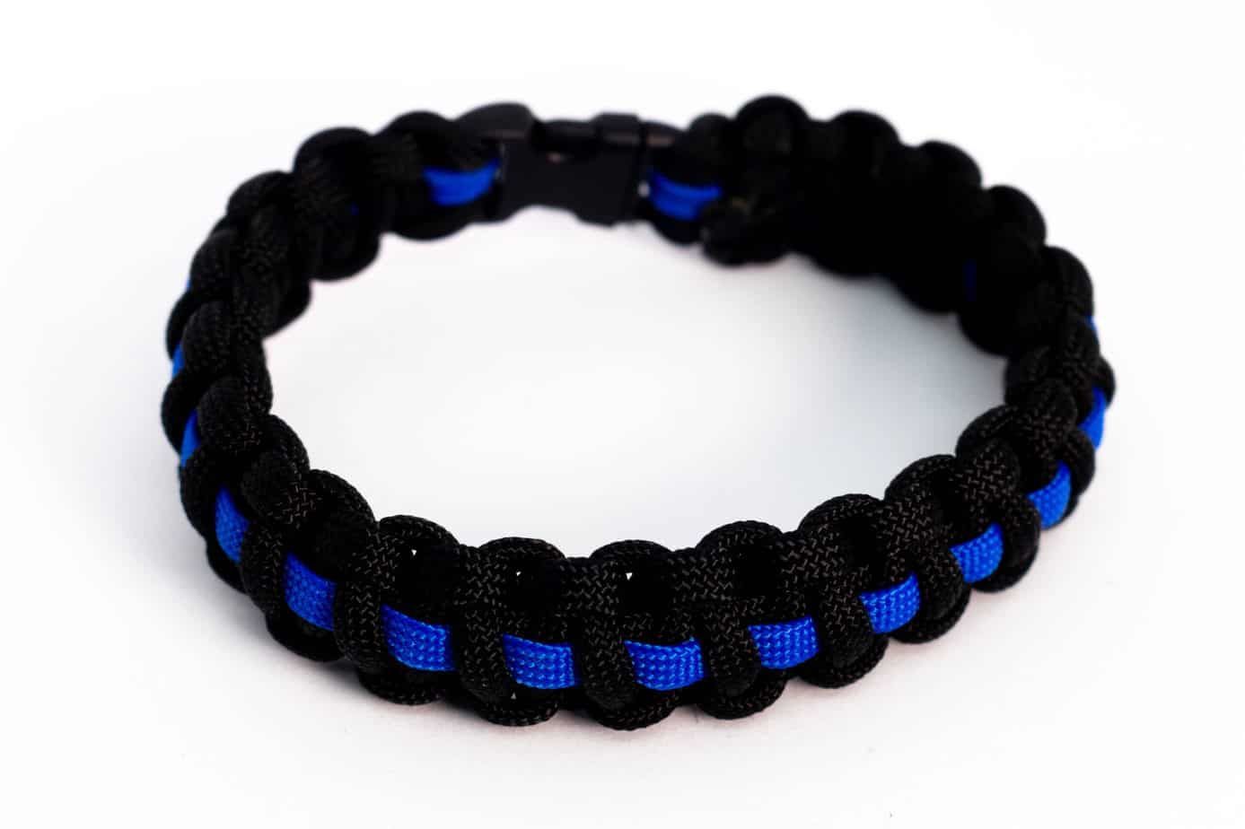 Black and blue paracord bracelet with a blue stripe, clasp fastened.