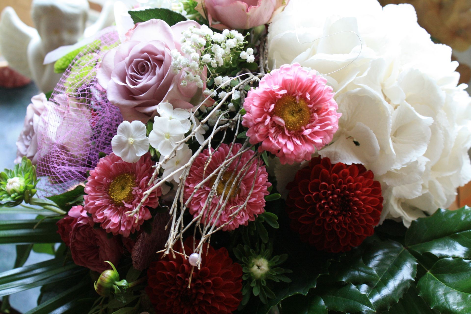 Close-up of a colorful bouquet featuring roses, dahlias, and hydrangeas in shades of pink, white, and burgundy.