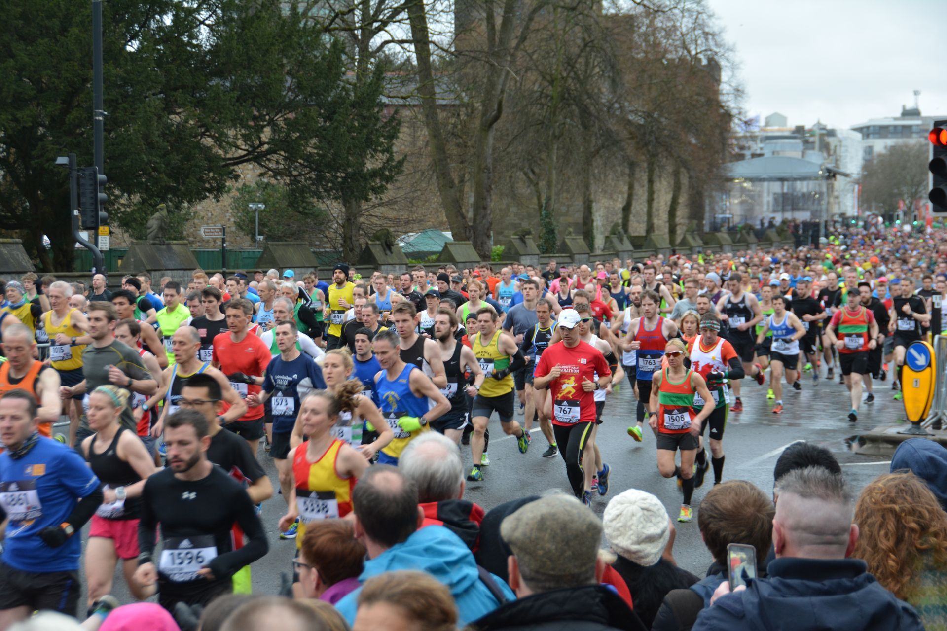 Large crowd running in a marathon on a city street with spectators.
