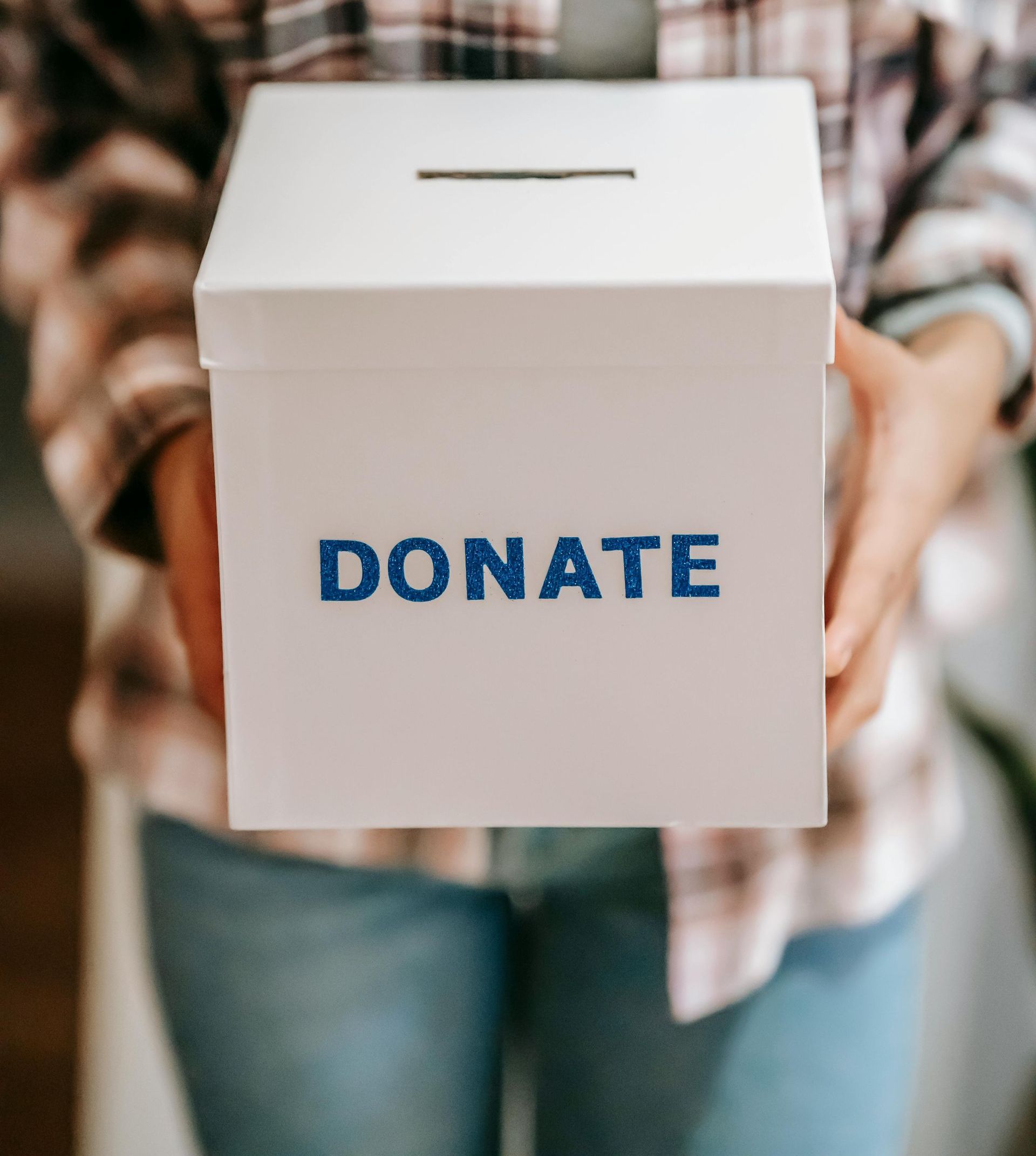 Person holding a white donation box with