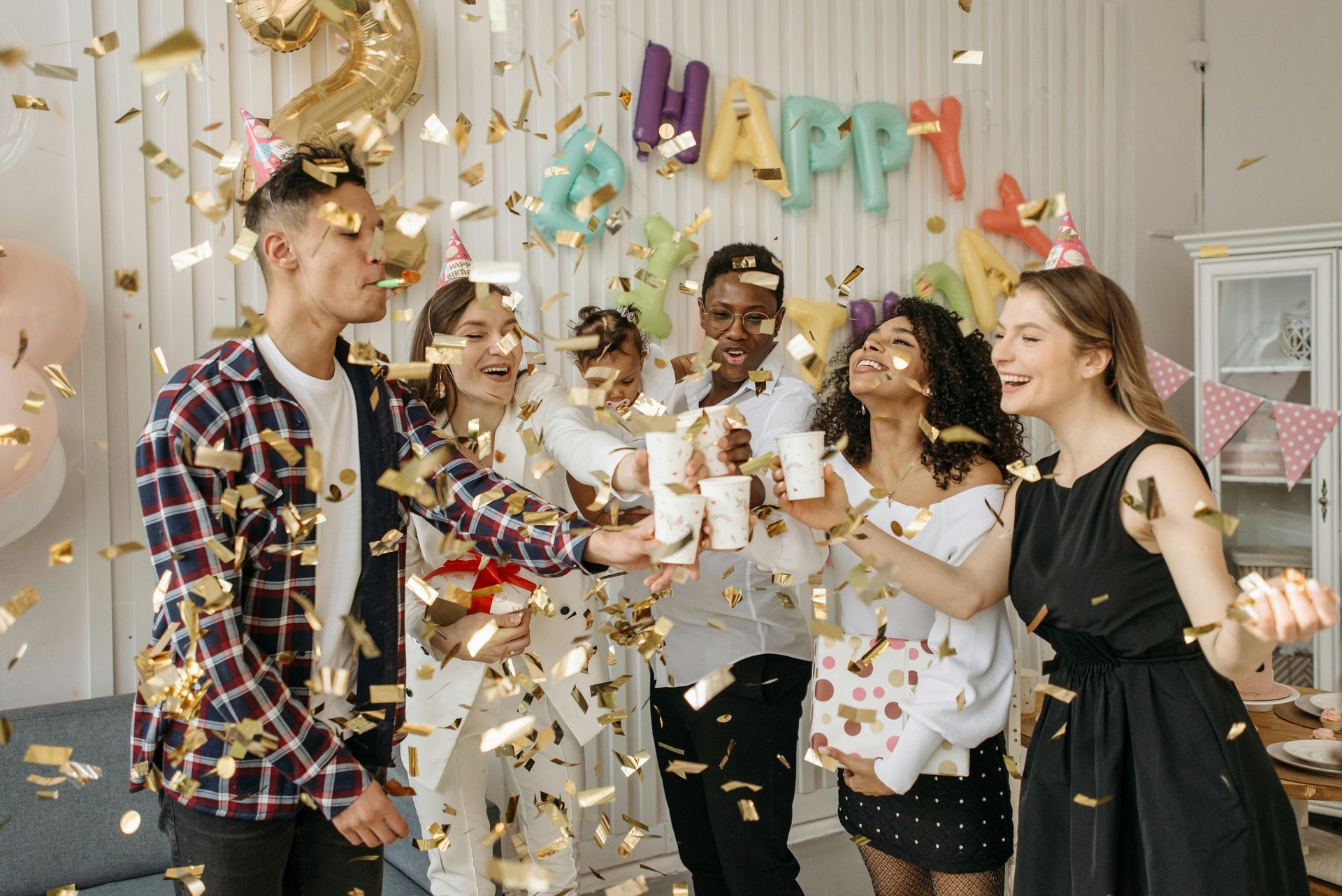 Group of friends celebrating with confetti at a birthday party.