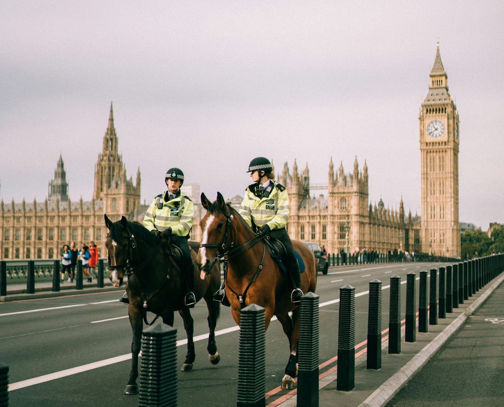 Two mounted police officers on a bridge with Big Ben and Parliament buildings in the background.
