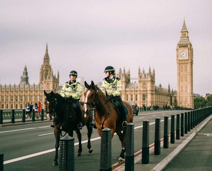 Two mounted police officers on a bridge with Big Ben and Parliament buildings in the background.