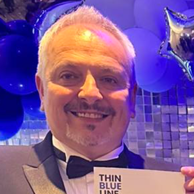Man in tuxedo smiling, with blue balloons and a 