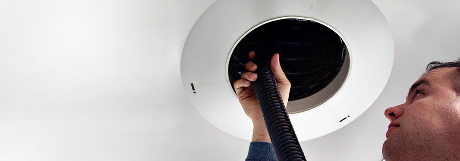 A Man is Cleaning a Vent With a Vacuum Cleaner