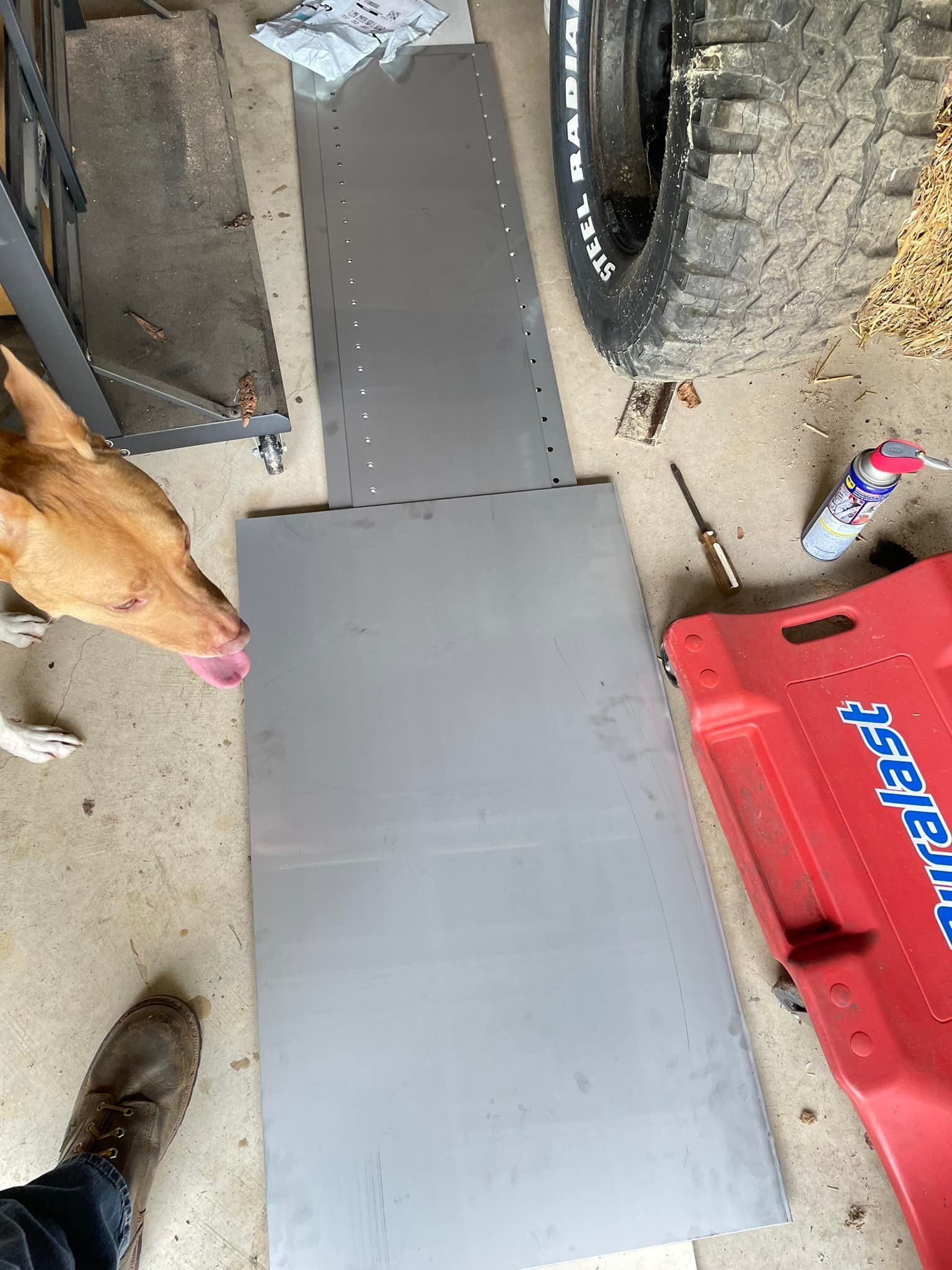 A dog is sniffing a piece of metal in a garage.