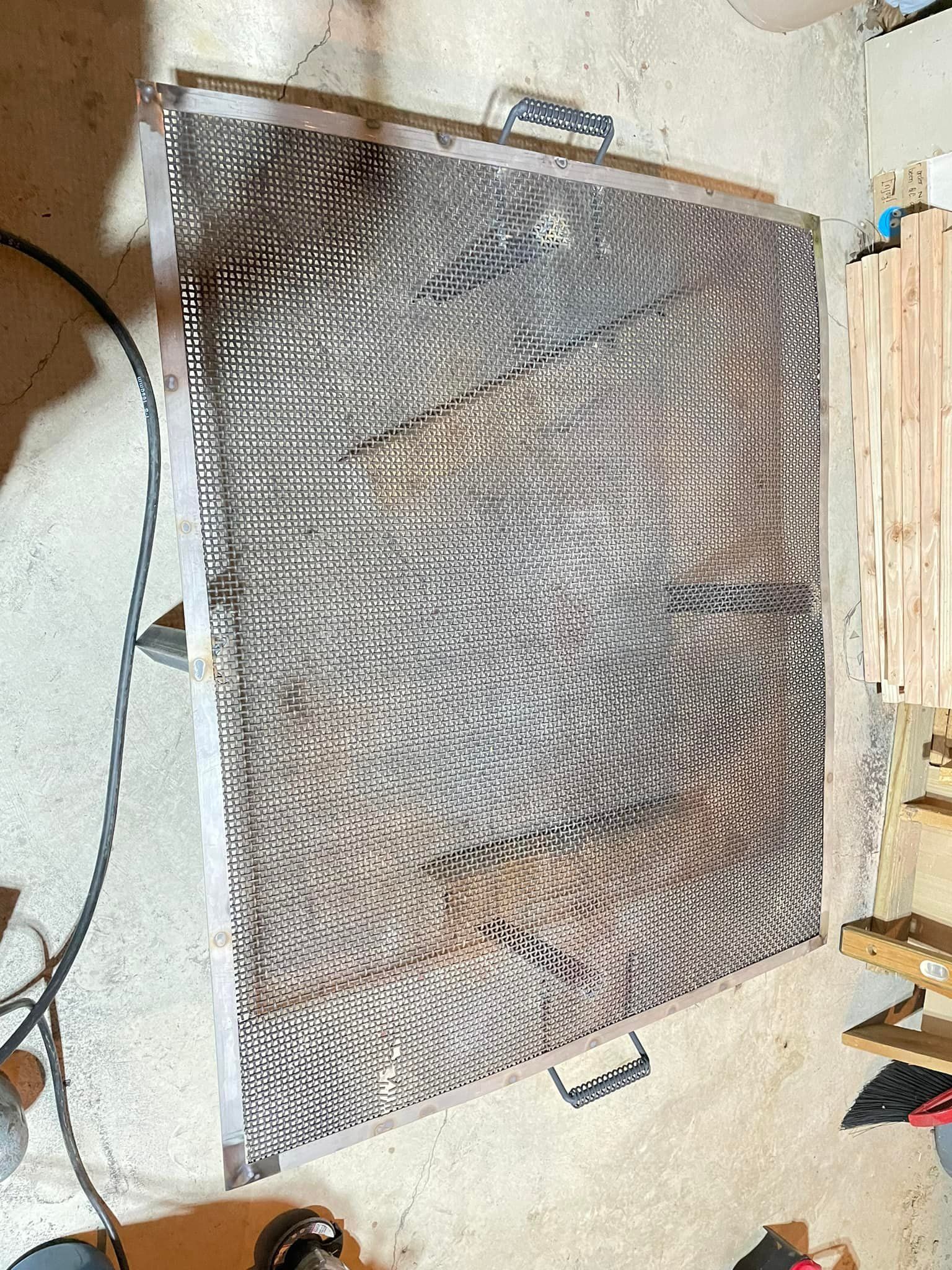 A piece of metal is sitting on the floor next to a wooden pallet.