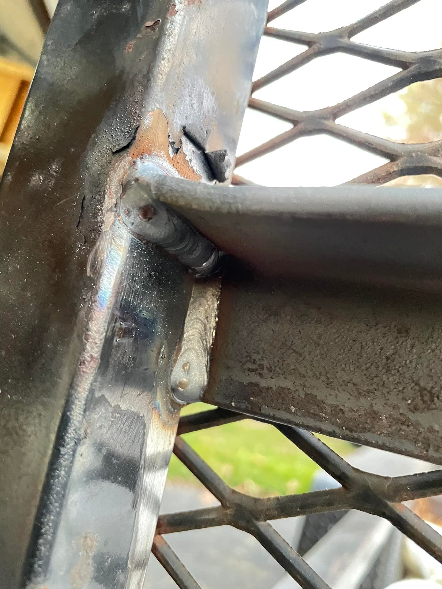 A close up of a metal structure with a fence in the background.