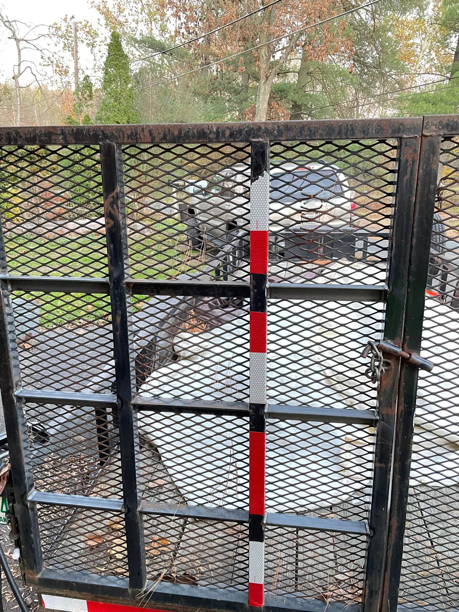 A car is parked in a driveway behind a metal gate.