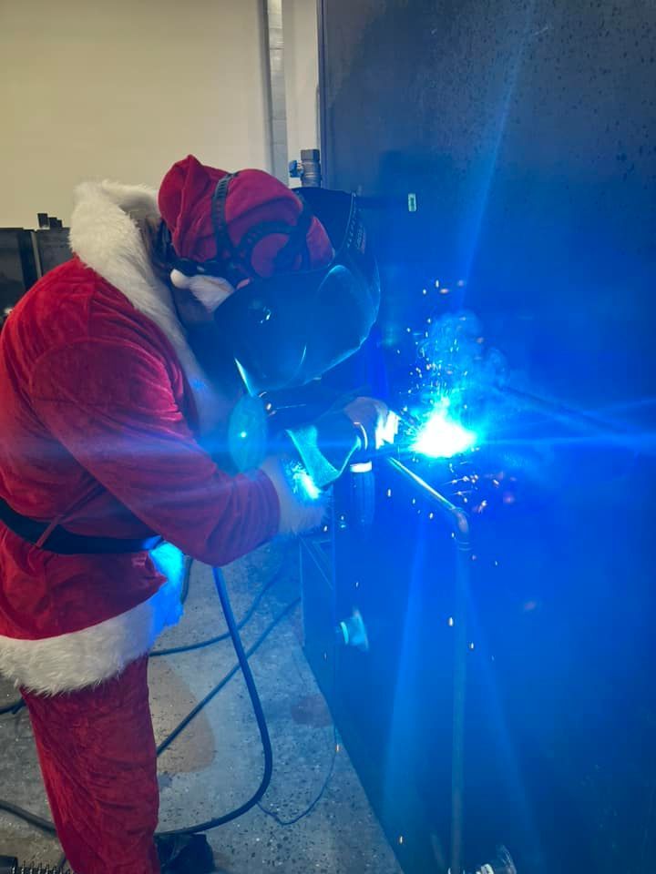 A man dressed as santa claus is welding a pipe.