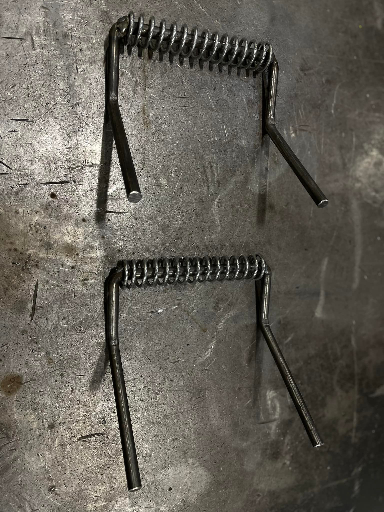 A pair of metal springs sitting on top of a metal surface.