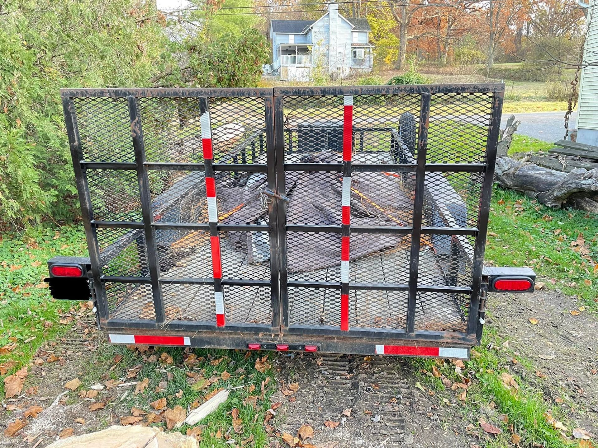 A trailer is parked in the grass in front of a house.