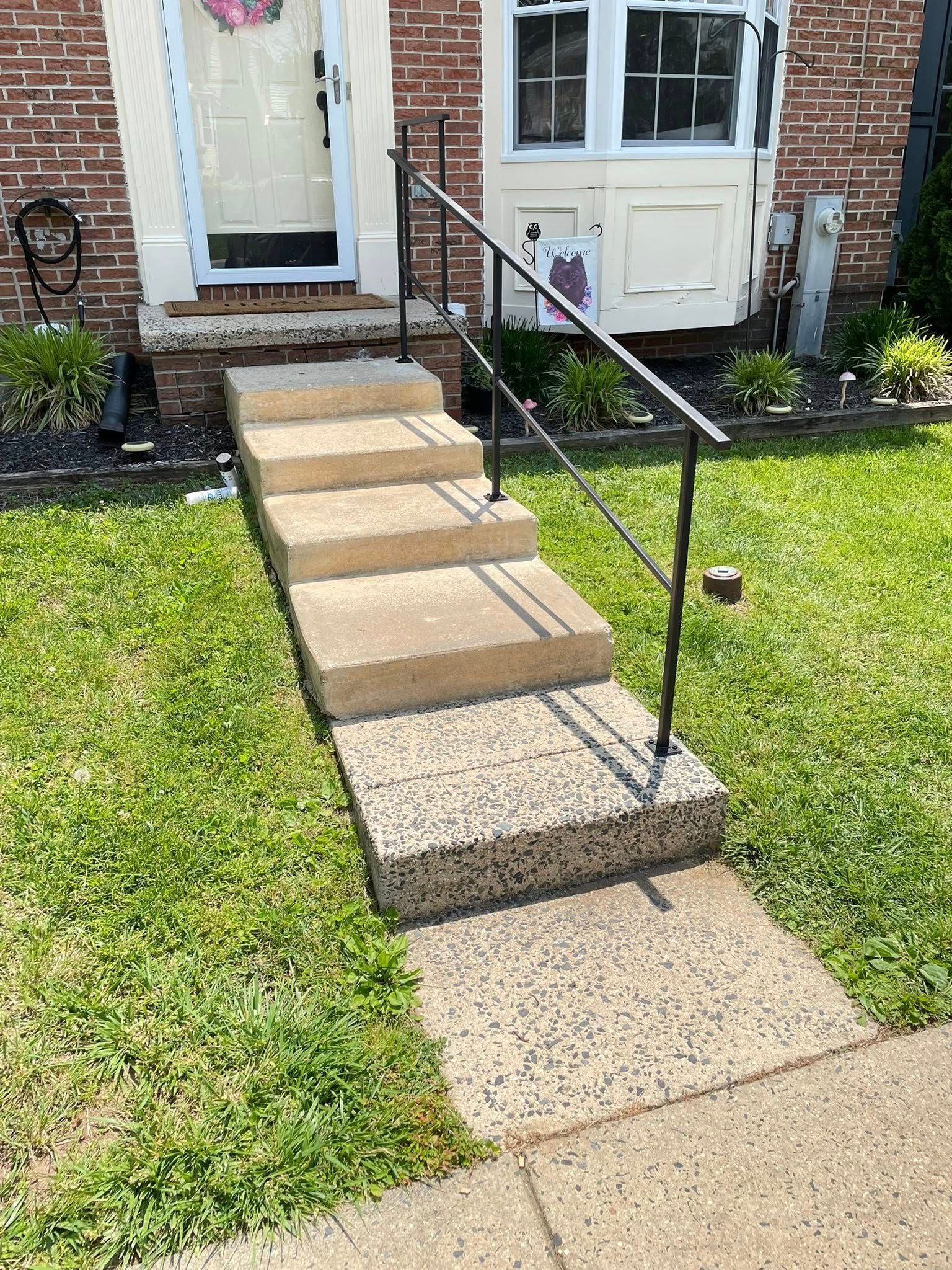 A set of stairs leading up to a brick house with a metal railing.