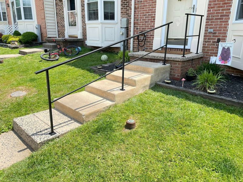 A set of stairs with a railing in front of a brick house.