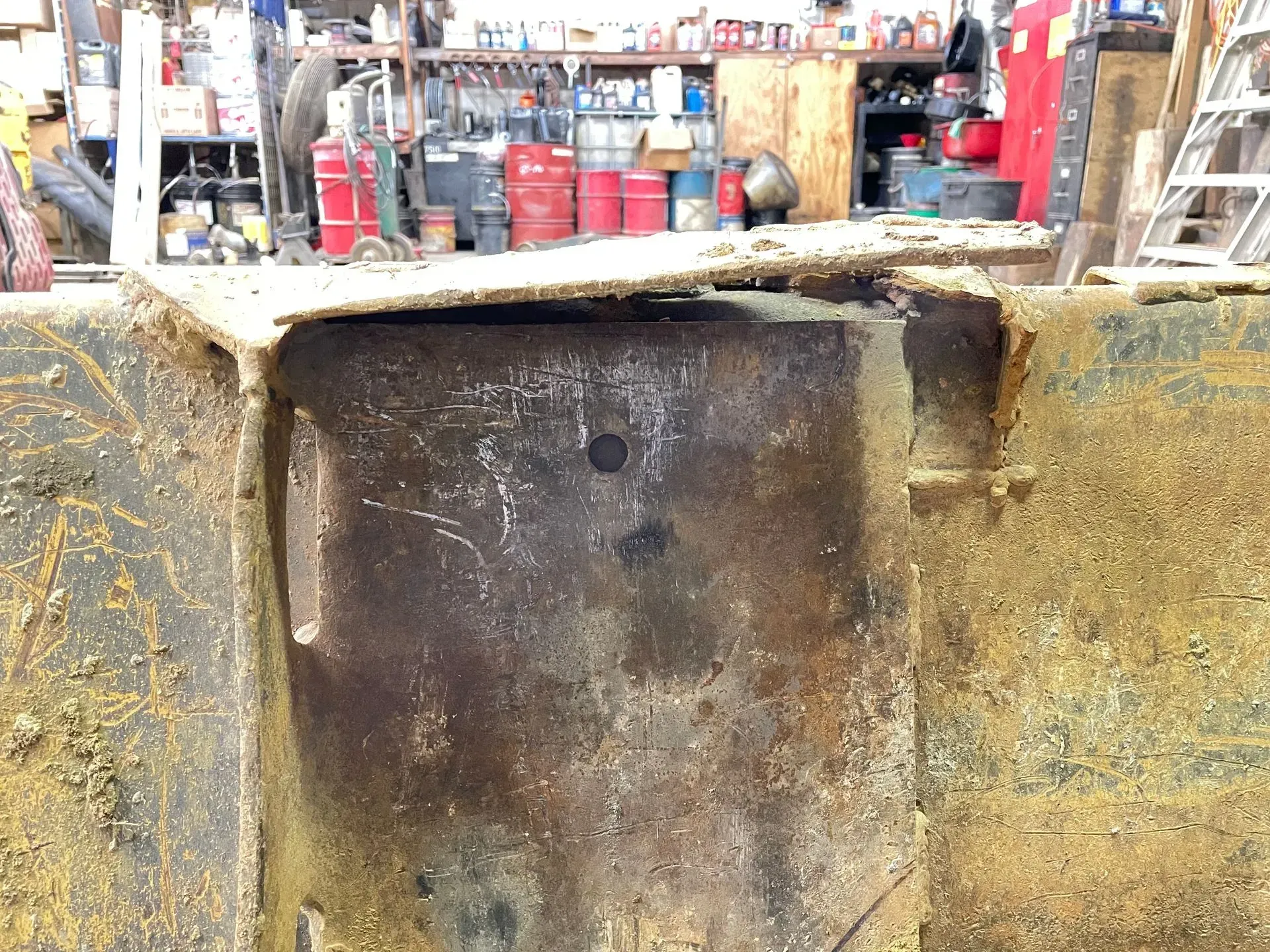 A large piece of rusty metal is sitting in a garage.