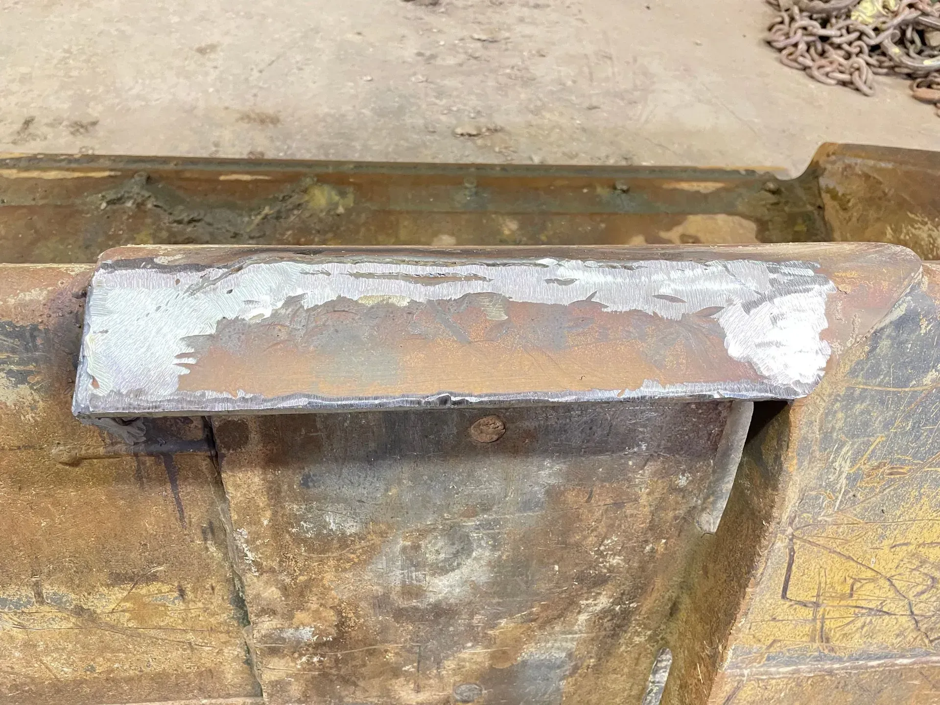 A piece of rusty metal is sitting on top of a wooden table.
