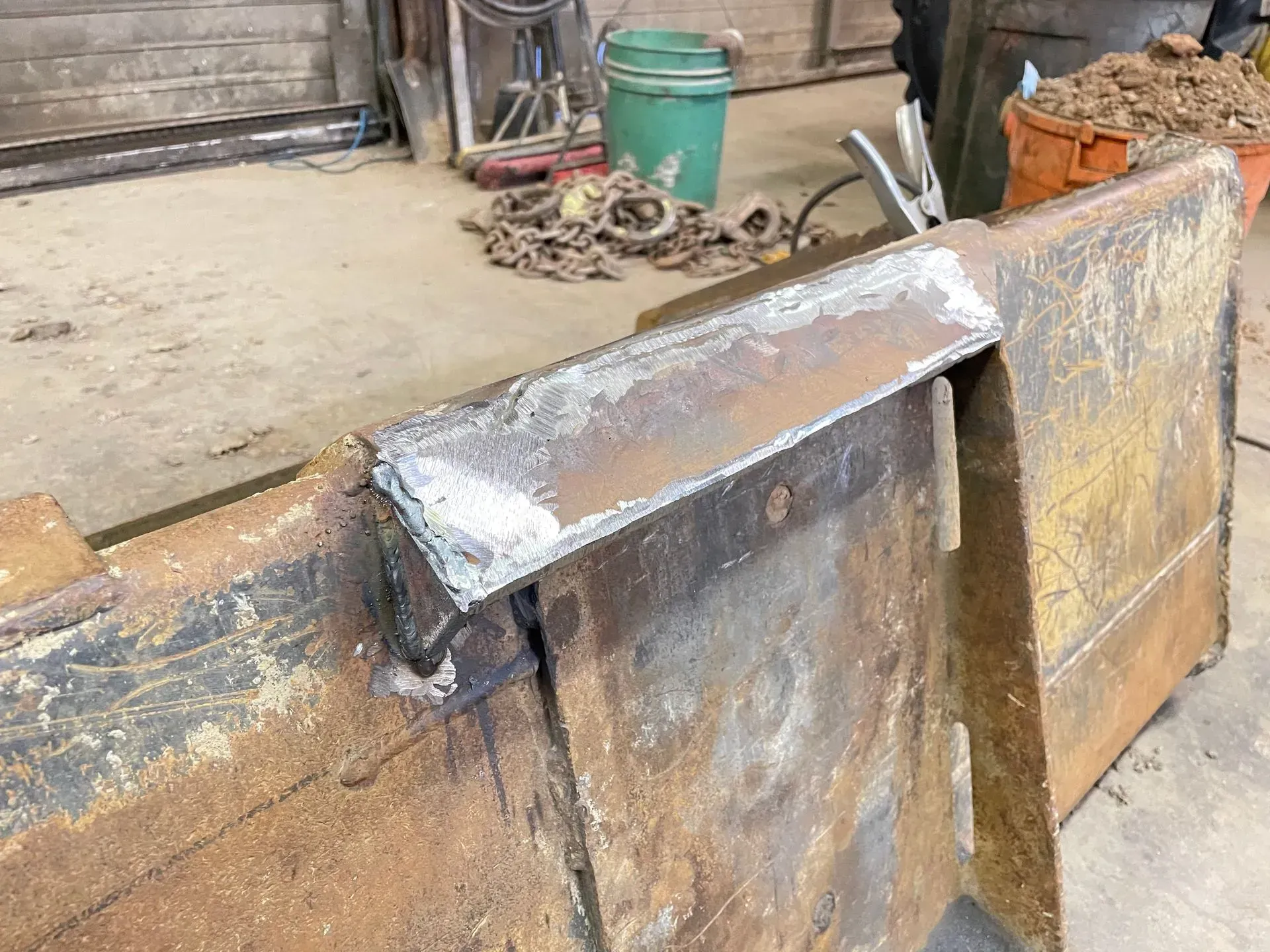 A piece of metal is sitting on the ground next to a green bucket.