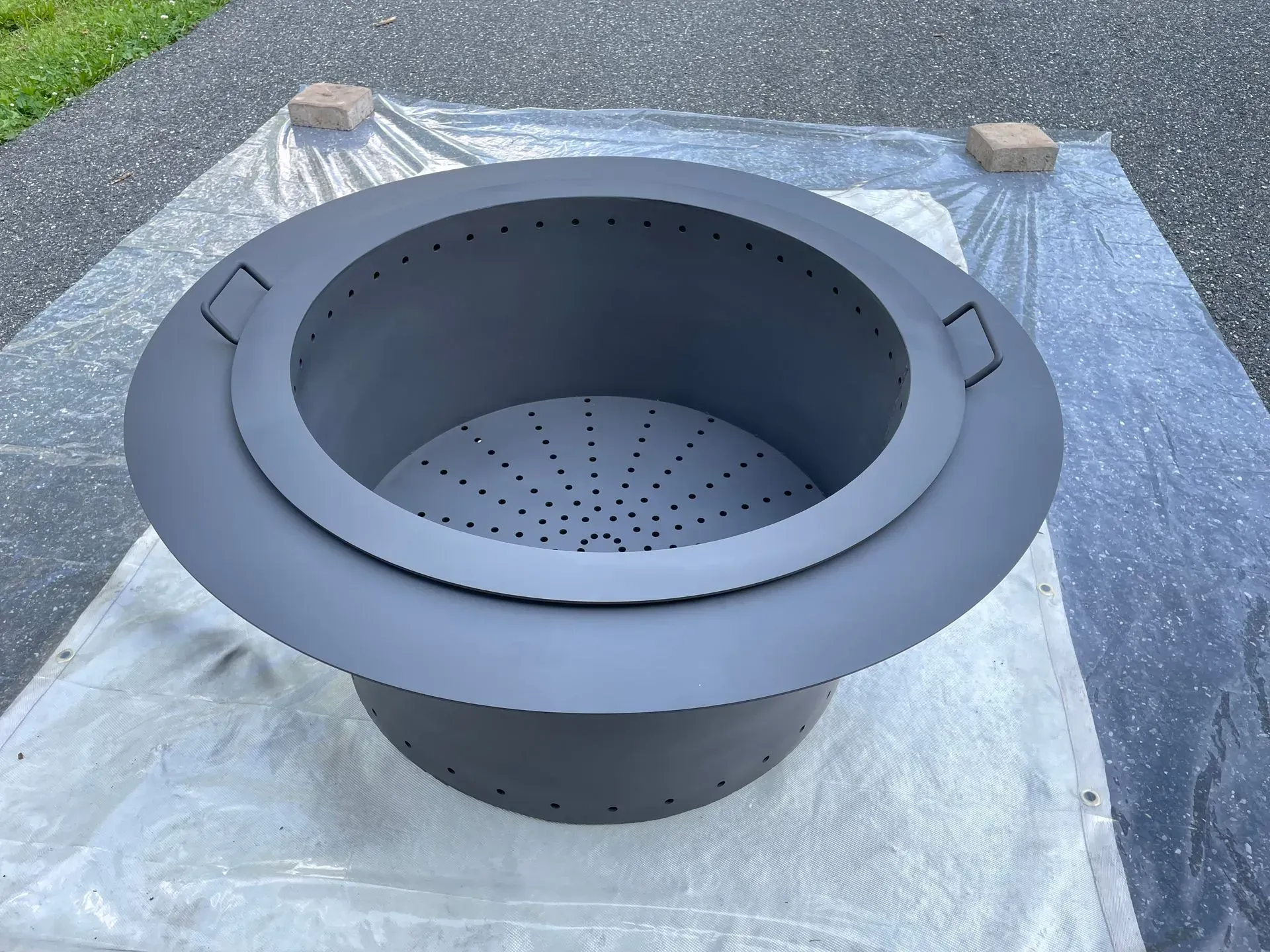 A black fire pit is sitting on a white tarp