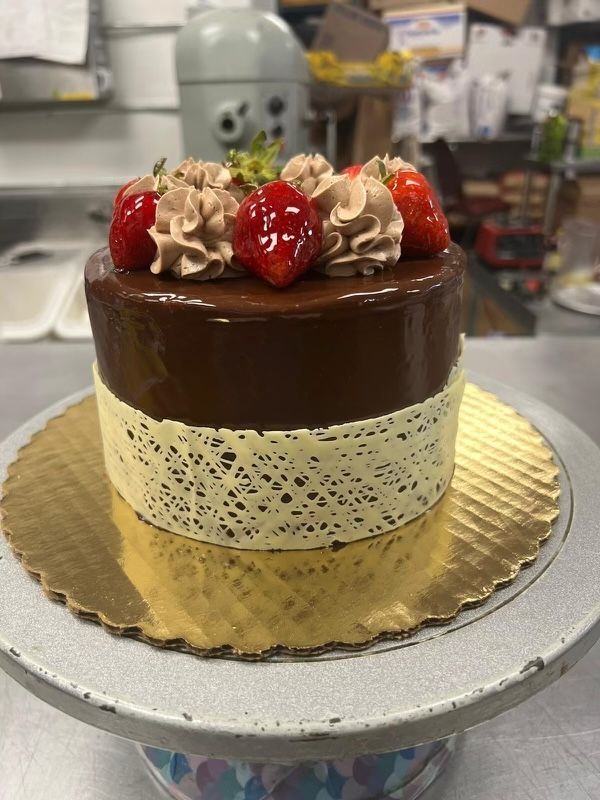 A chocolate cake with strawberries on top is on a cake stand.