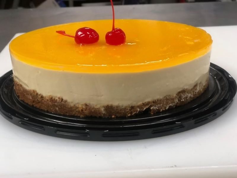 A cheesecake with two cherries on top of it