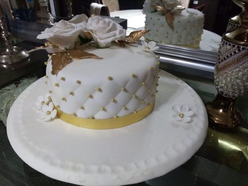 A white cake with gold polka dots and flowers on it