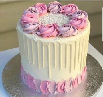 A white cake with pink frosting is sitting on a silver plate.