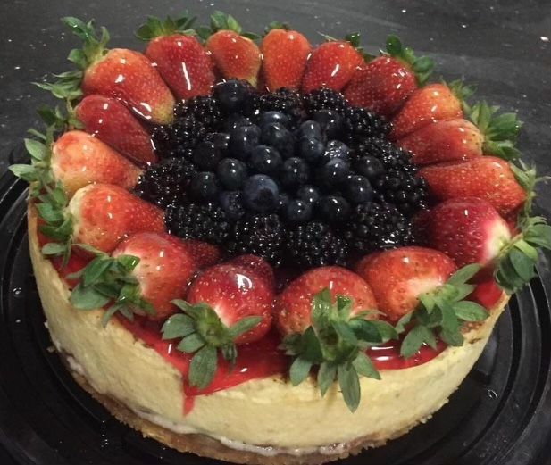 A cheesecake with strawberries blueberries and blackberries on top
