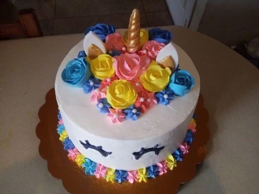 A unicorn cake with flowers and a horn on top