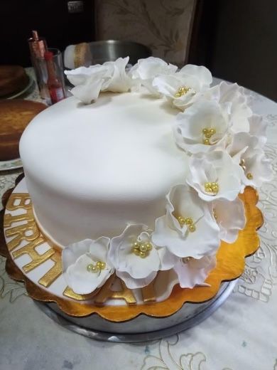 A white cake with white flowers and the word happy on it