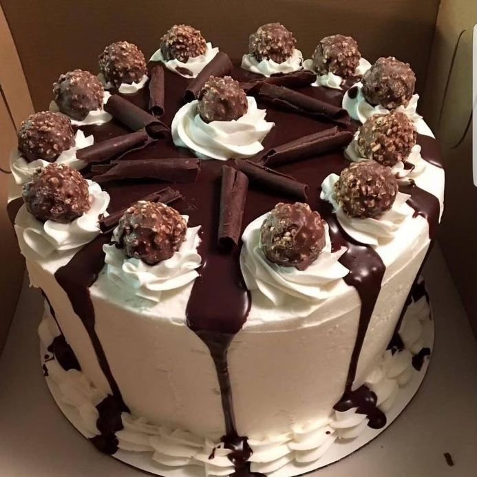 A white cake with chocolate frosting and chocolate balls on top