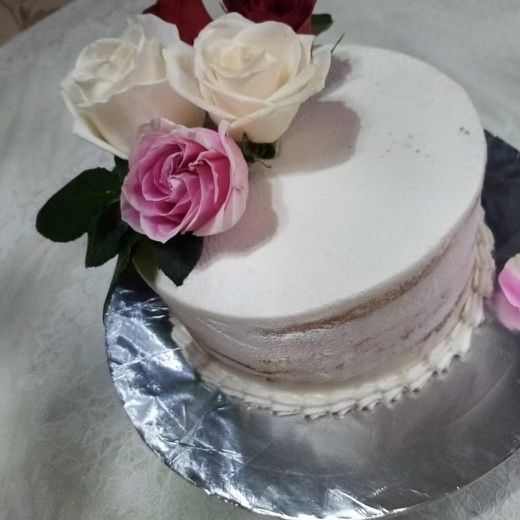 A white cake with pink and white roses on top
