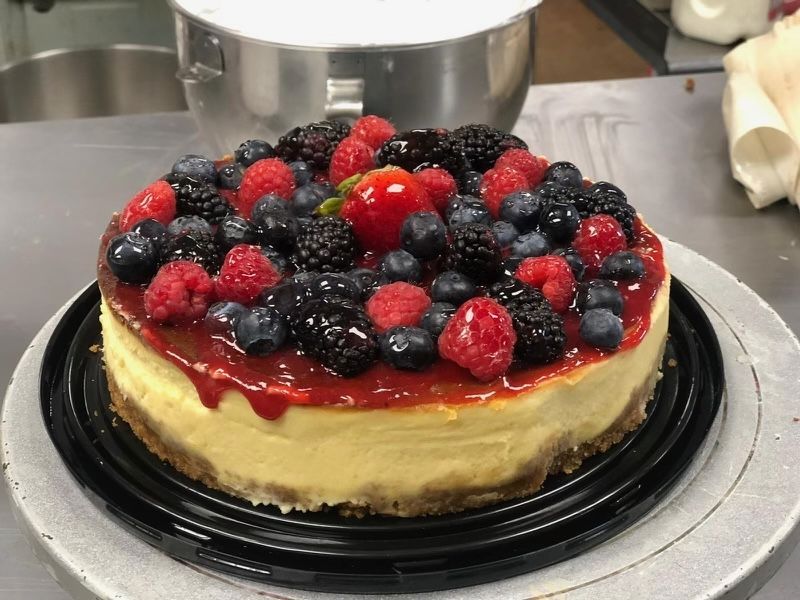 A cheesecake with raspberries , blackberries and blueberries on top