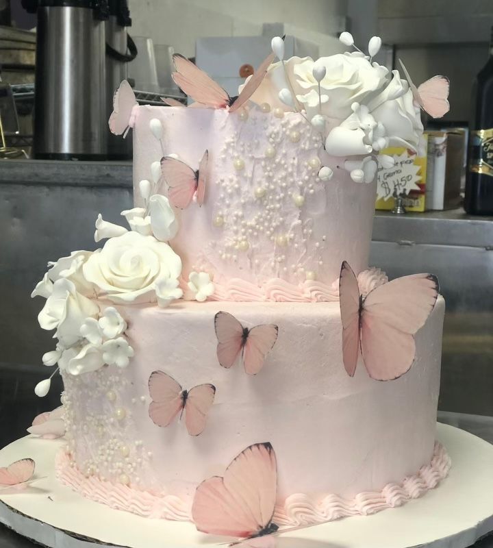 A pink cake with butterflies and flowers on it