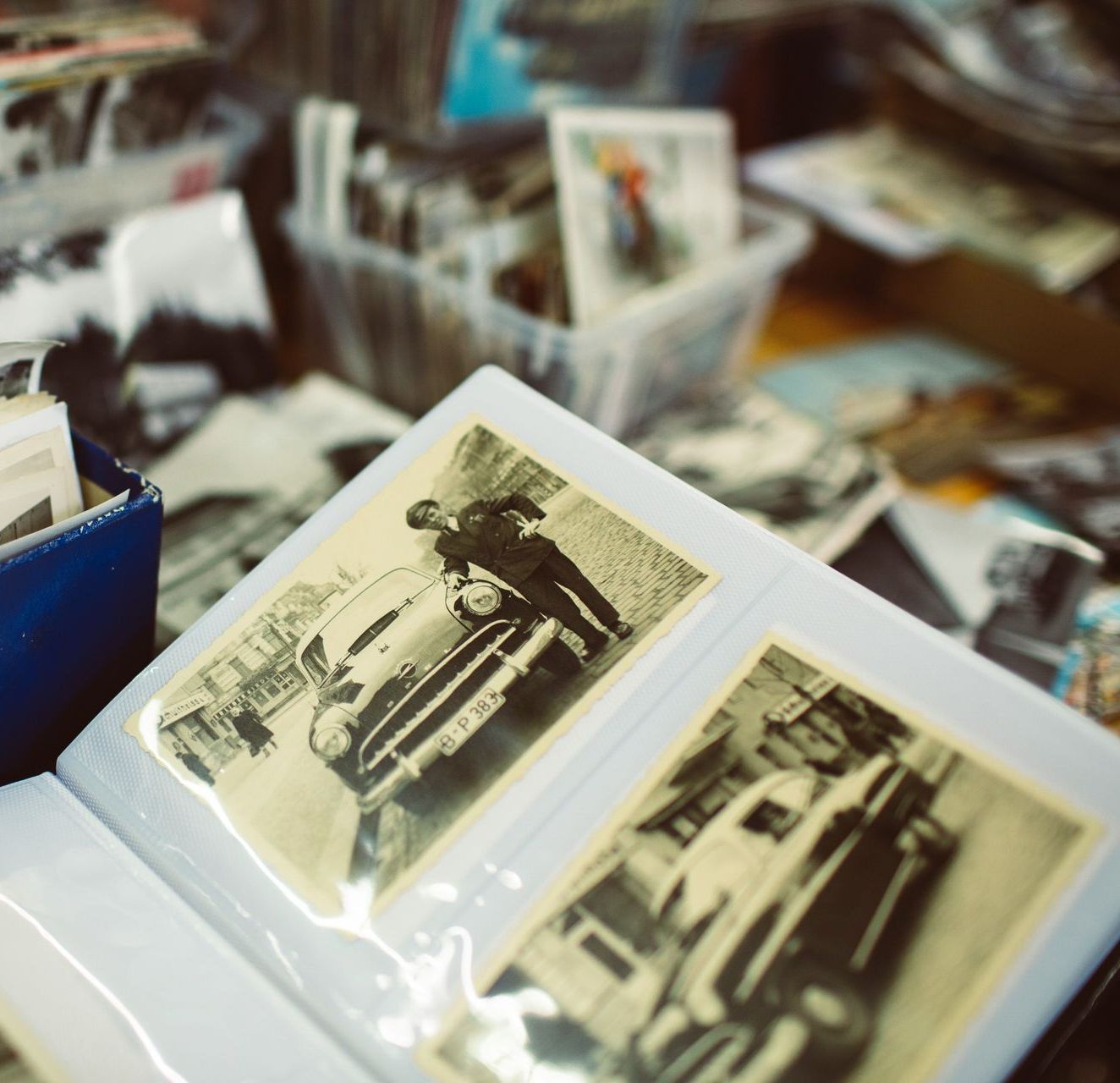 Vintage photo album showing black-and-white snapshots of cars, with a person standing next to a vehicle.
