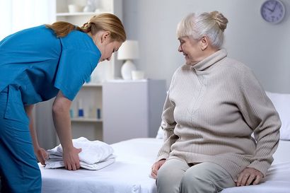 Nurse Preparing Clean Bed-linen To Elderly Female Patient — Hyannis, MA — Cherry's Home Care