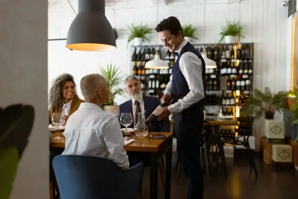 a waiter is serving a group of people in a restaurant .