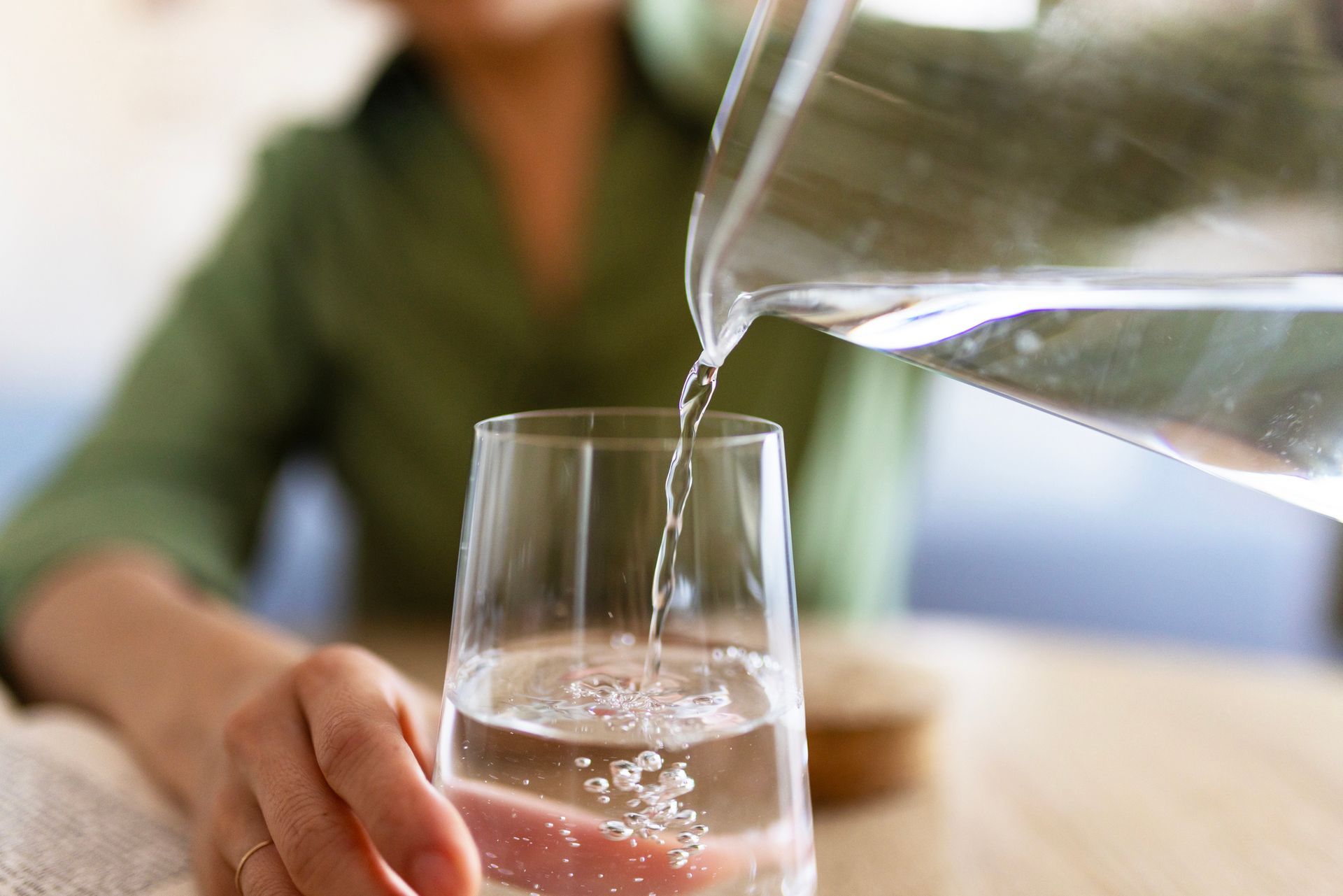 Woman pouring water into glass after Mallard installed a professional water filtration system.