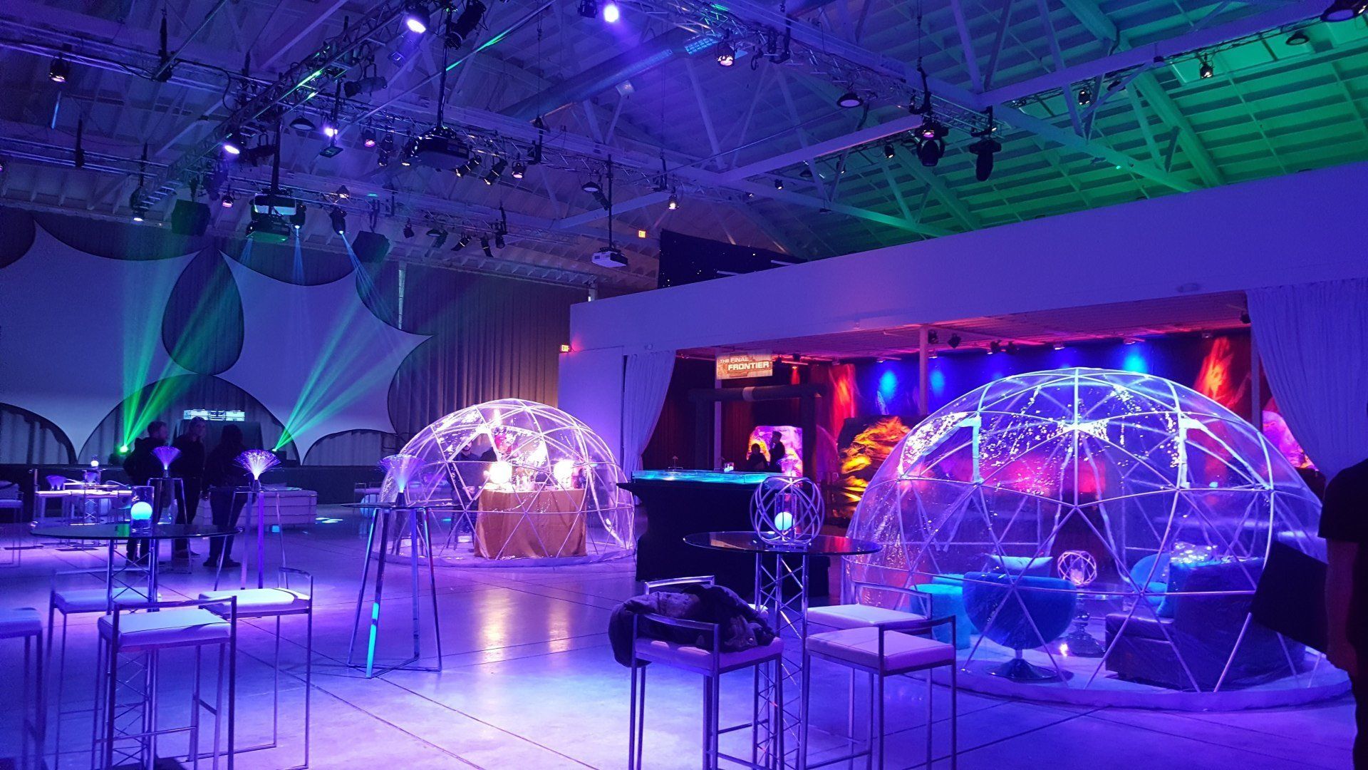 An event hall with igloo-like structures, tables, and colorful stage lighting.