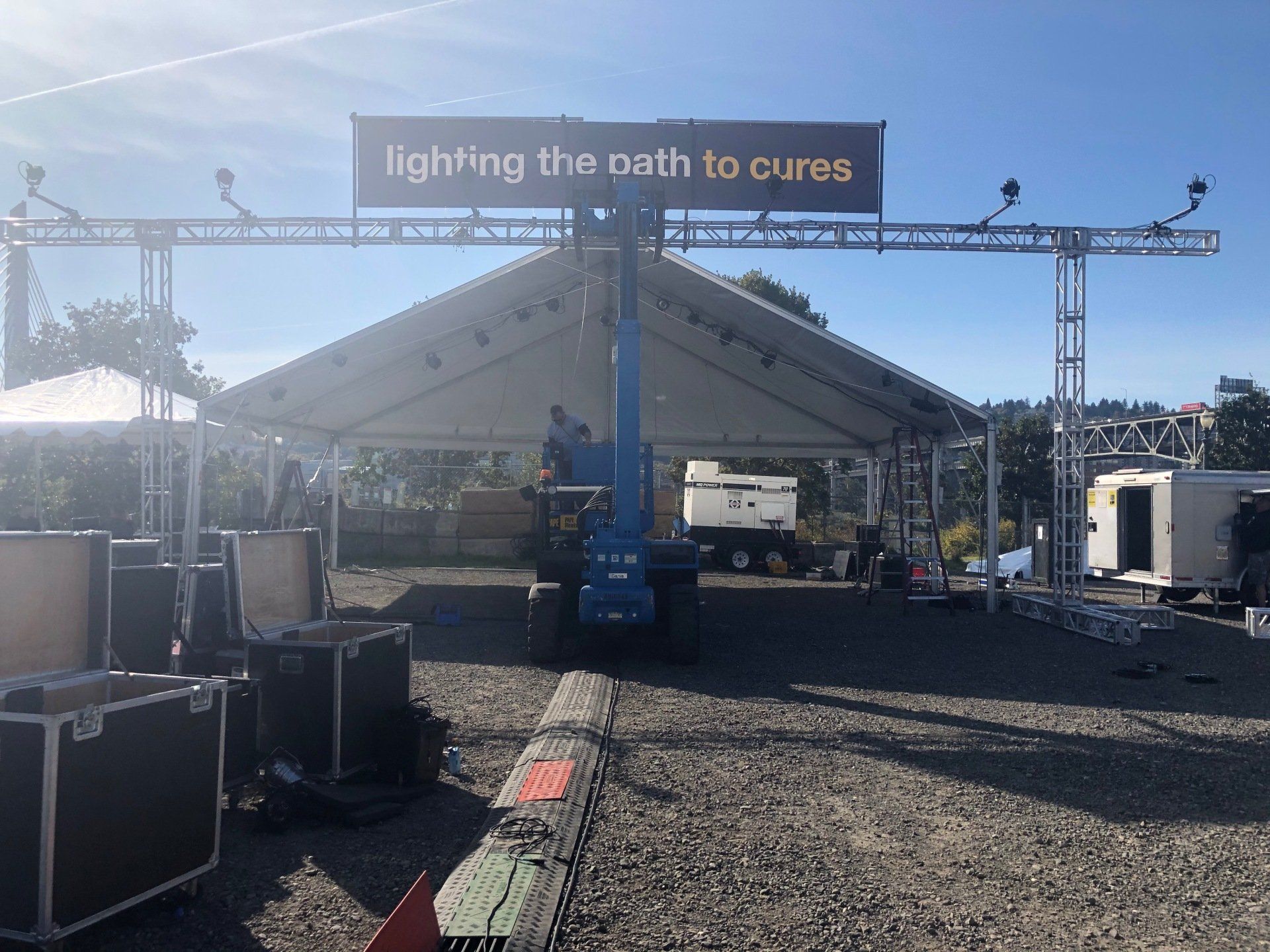 A tent and stage are being set up outdoors. A sign reads 