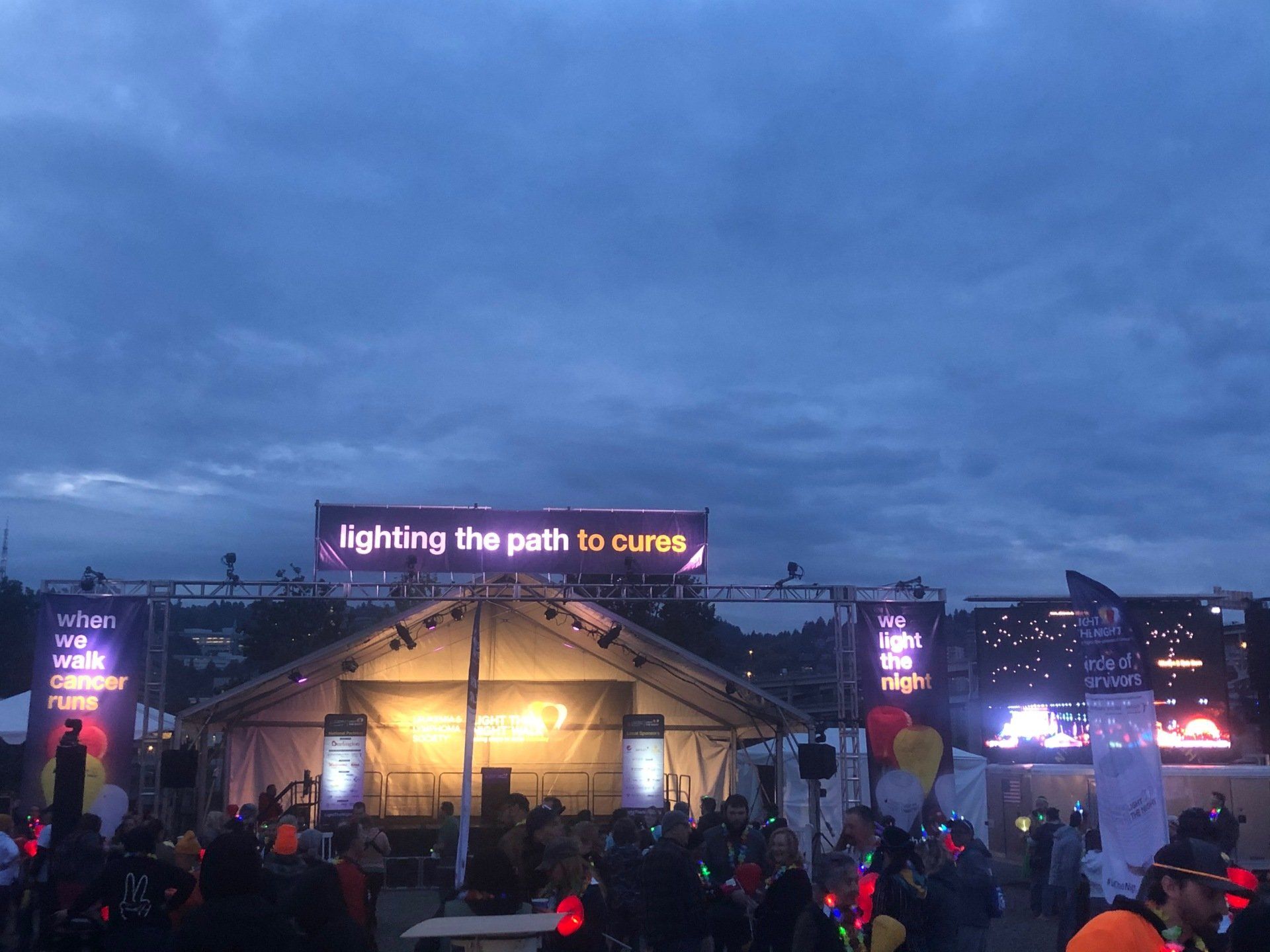 Night outdoor event with lit stage, banner