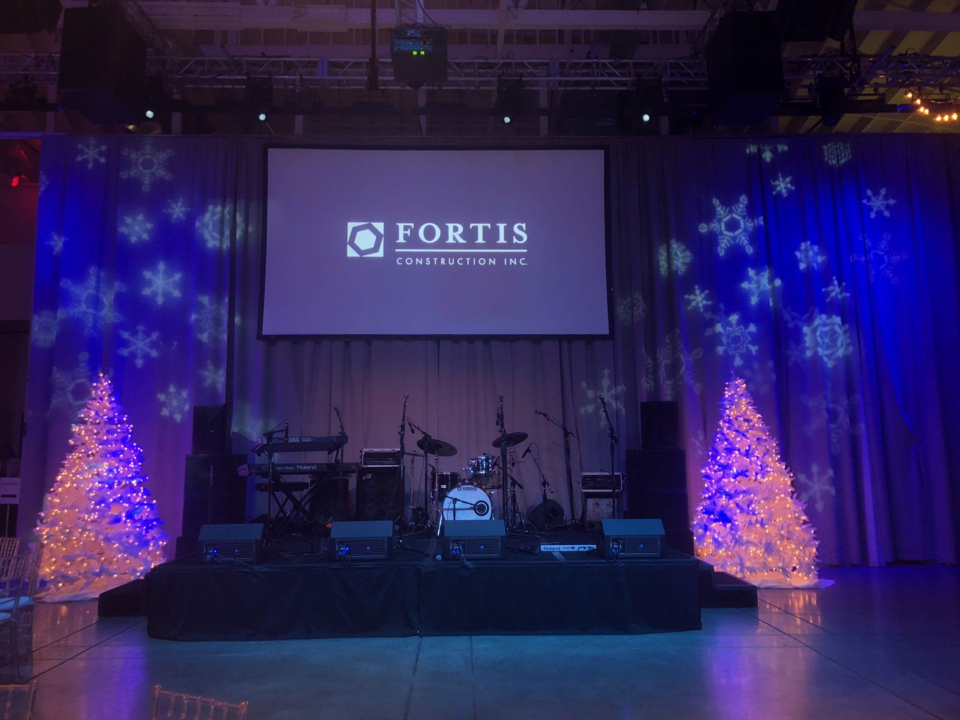 Stage with a band setup for a Fortis event; blue and white lighting, Christmas trees, snowflakes.