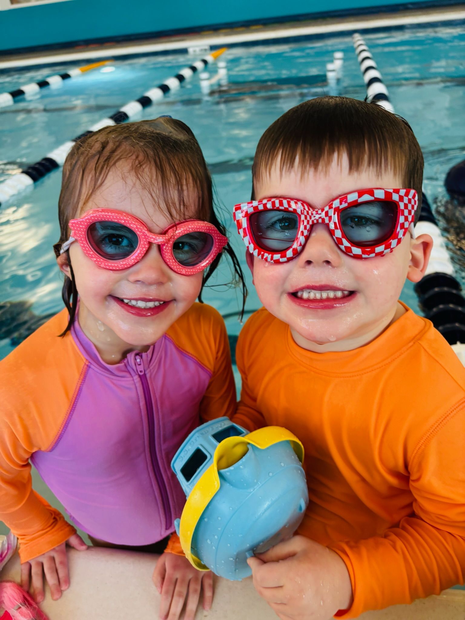 A group of kids and a swim instructor in a swimming pool.