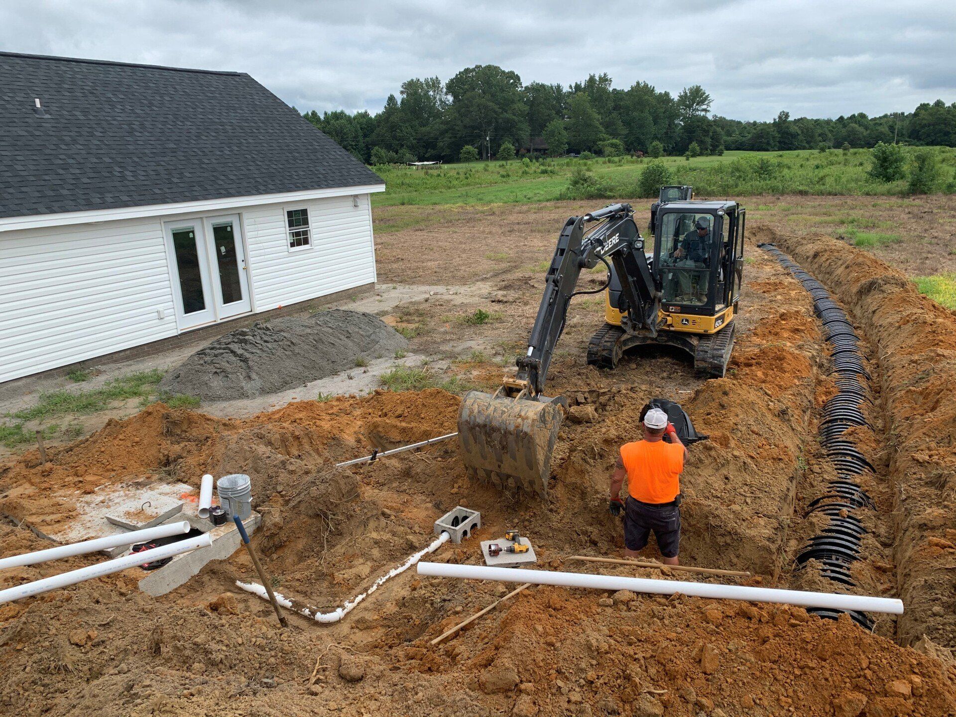 A man is digging a hole in the dirt in front of a house.
