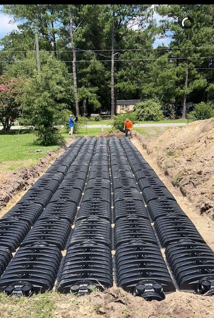 A row of black pipes are sitting in the dirt in a field.