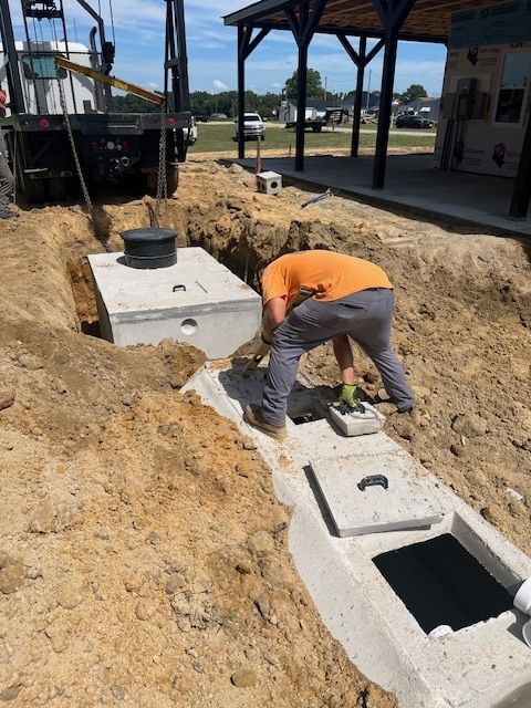 A man is working on a septic tank in the dirt