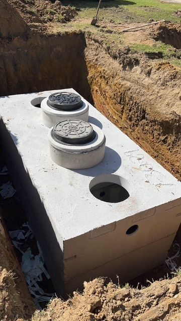 A concrete septic tank is sitting in a hole in the ground.